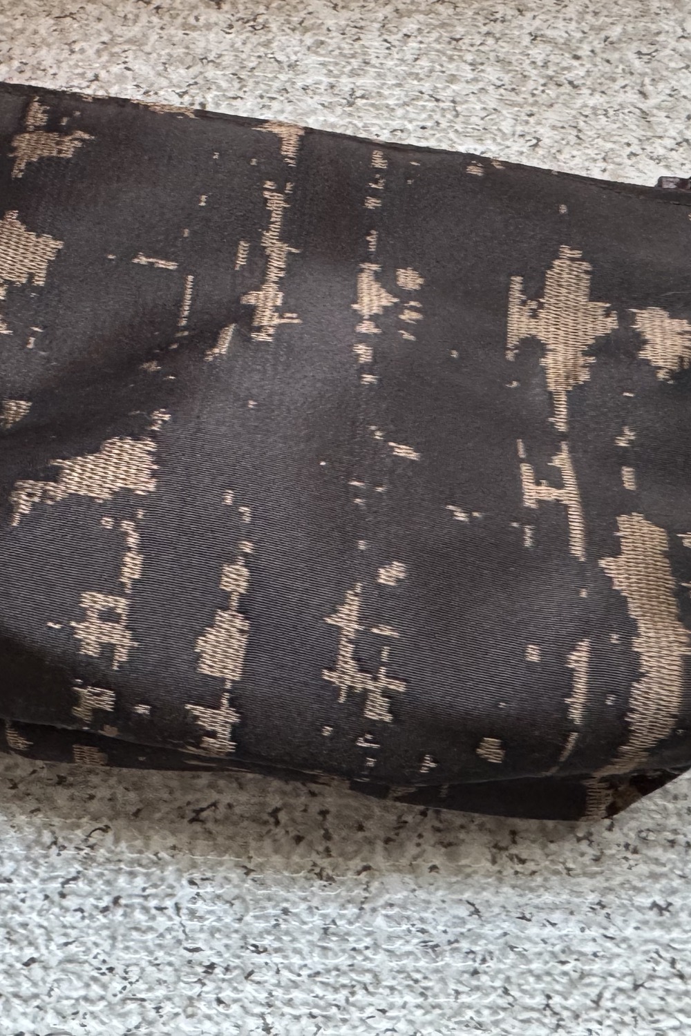 Macro detail of black silk damask fabric with a gold weave pattern.